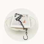 Black metal zipper hook on a white plate with a white background