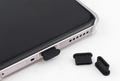 Smartphone with black rubber plug and additional black rubber plugs on a white background