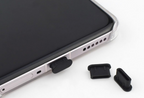 Smartphone with black rubber plug and additional black rubber plugs on a white background