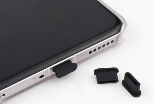 Smartphone with black rubber plug and additional black rubber plugs on a white background